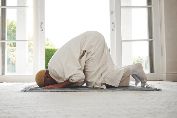 Prayer, muslim and islamic with man on living room floor for eid mubarak, God and worship. Quran, hope and Ramadan with spiritual person praying on mat at home for faith, religion and gratitude. - Фото, изображение
