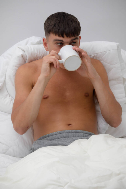 若いですシングル大人男飲むコーヒーでベッド - 写真・画像