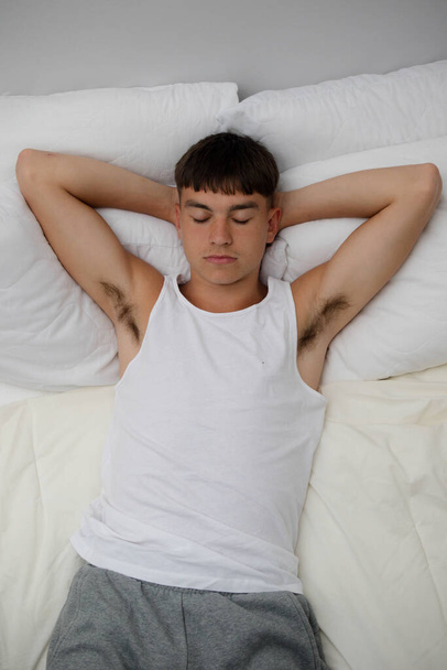 Young single male adult asleep on top of his bed - Foto, afbeelding