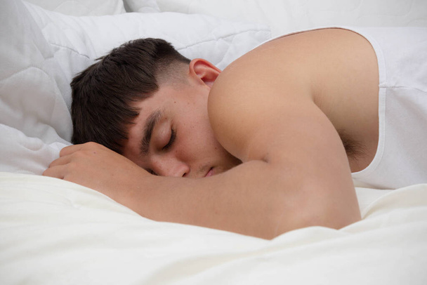 Young single male adult asleep on his front,on top of his be - Foto, imagen