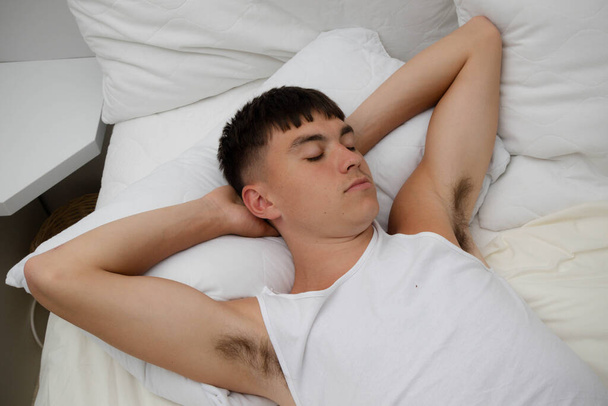 Junge alleinstehende männliche Erwachsene schlafen in seiner Kleidung, auf seinem Bett - Foto, Bild
