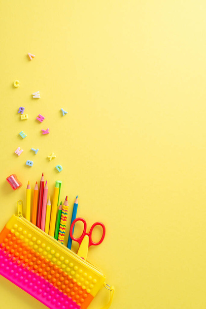 Step into the realm of education with captivating top vertical photograph featuring a child's workplace with various colorful stationery on isolated yellow background, ready for text or advertising - Photo, Image
