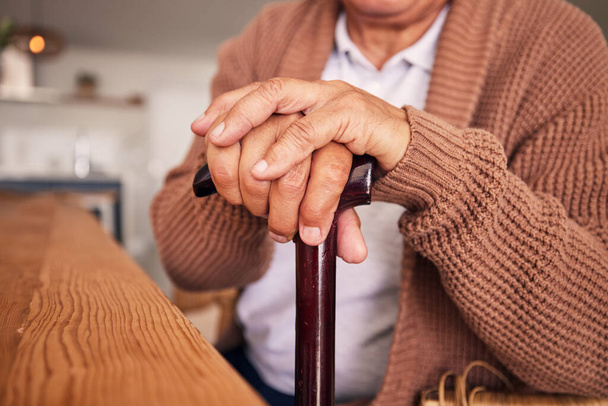 Closeup, handen en riet van persoon met een handicap, artritis en hulp van osteoporose, parkinson of beroerte. Pensioen, senior patiënt en wandelstok met ondersteuning, hulp of mobiliteit in de gezondheidszorg. - Foto, afbeelding