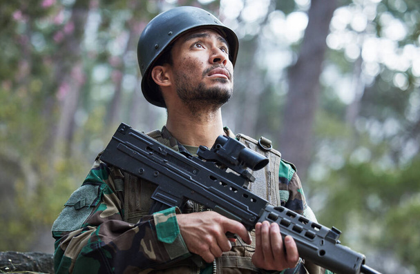 Soldier, army and man thinking with gun in forest training, outdoor shooting or military exercise, mission and focus. Rifle, veteran and young person search woods or nature in battlefield gear vision. - Photo, Image