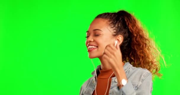 Woman, dancing and listening to music on green screen for streaming against a studio background. Happy female person with earphones enjoying audio, radio or sound track for fun on mockup space. - Footage, Video
