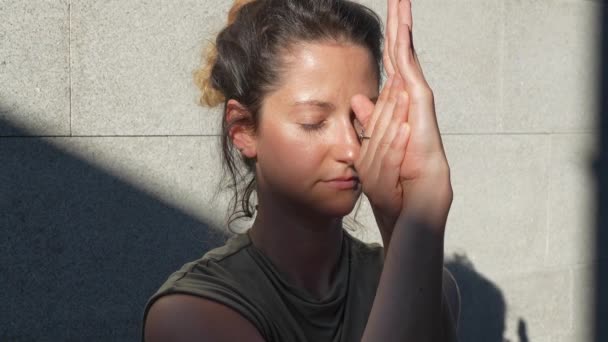 Jedna dospělá běloška dělá jógu strečové cvičení v letním dni venkovní ve městě před zdí se stínem a sluncem zdravý životní styl koncept sebepéče  - Záběry, video
