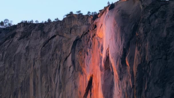 Scenic view of Yosemite Firefall lighting by sunset sun, Yosemite Nemzeti Park, Kalifornia, USA. Csodálatos Lófarok esik az esti órákban. Természetes háttér másolási hellyel. Panning lövés 4k  - Felvétel, videó