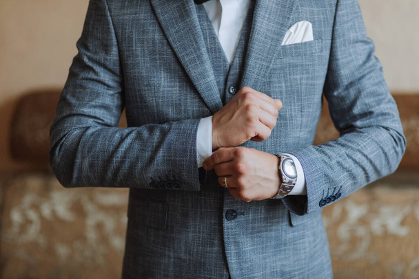 The stylish bridegroom dresses, prepares for the wedding ceremony. The groom's morning. Businessman wears a jacket, male hands closeup, groom getting ready in the morning before wedding ceremony - Φωτογραφία, εικόνα