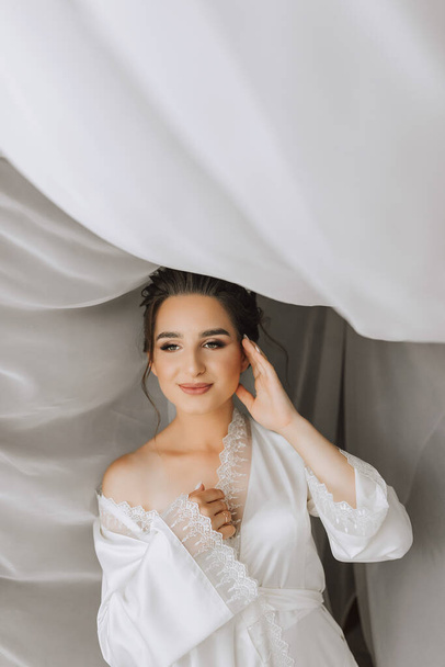 Beautiful bride. Wedding hairstyle - on a white background. Close-up portrait of a young gorgeous bride. Wedding. Portrait of a beautiful bride wrapped in a veil - Foto, imagen