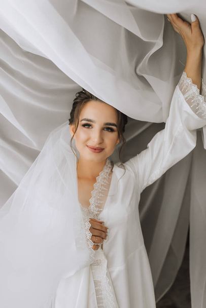 Beautiful bride. Wedding hairstyle - on a white background. Close-up portrait of a young gorgeous bride. Wedding. Portrait of a beautiful bride wrapped in a veil - Photo, Image