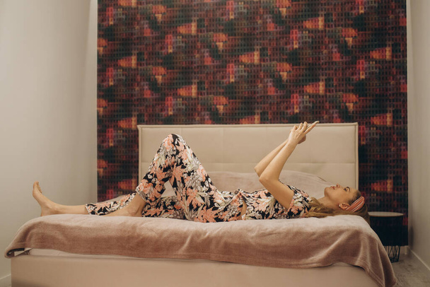 Fiatal lány fekszik az ágyban a mobiltelefonjával - Fotó, kép
