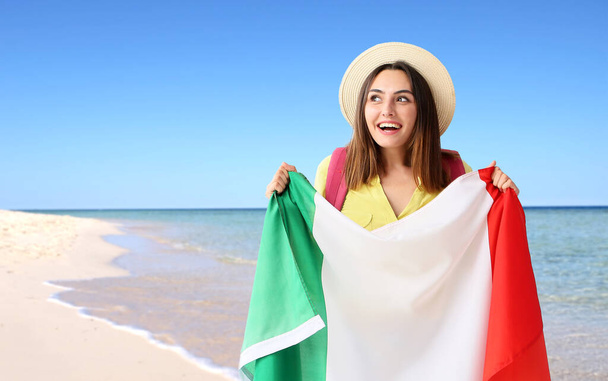 海のビーチでイタリアの旗を持つ女性観光客 - 写真・画像