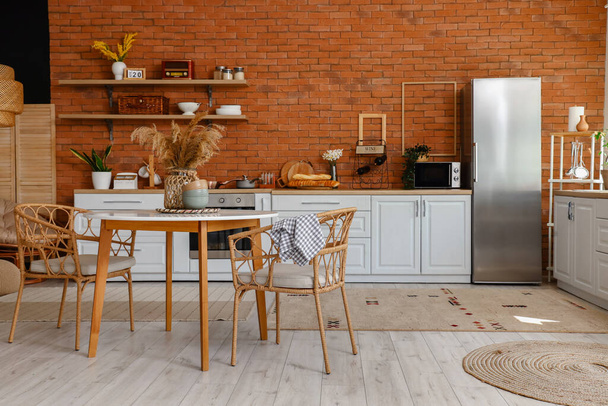 Інтер'єр кухні зі стильним холодильником, лічильниками, полицями, столом і стільцями
 - Фото, зображення