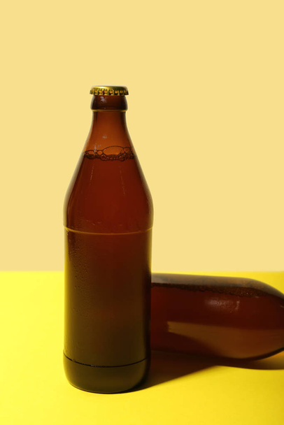 Бутылки холодного пива на желтом фоне, крупный план - Фото, изображение