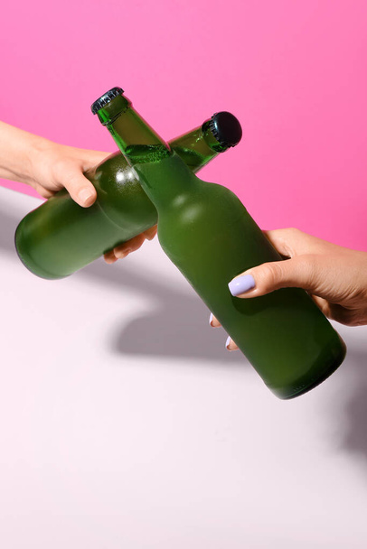 Female hands with bottles of cold beer on pink background - Valokuva, kuva