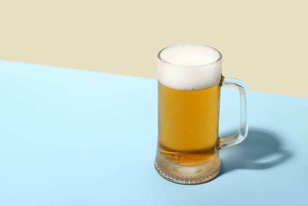 Mok koud bier op kleur achtergrond - Foto, afbeelding