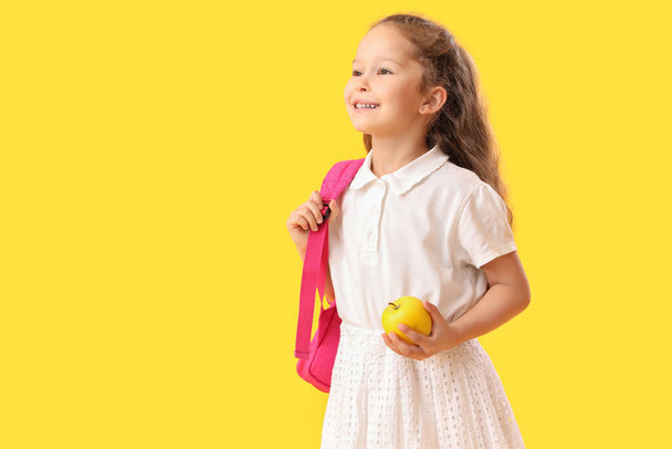Little schoolgirl with apple on  yellow background - Фото, зображення