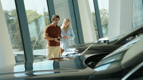 Νεαρό ζευγάρι ψάχνει για SUV ή crossover αυτοκίνητο στην έκθεση αντιπροσωπείας λαμβάνοντας φωτογραφίες του μοντέλου αυτοκινήτου που ενδιαφέρονται για - Πλάνα, βίντεο