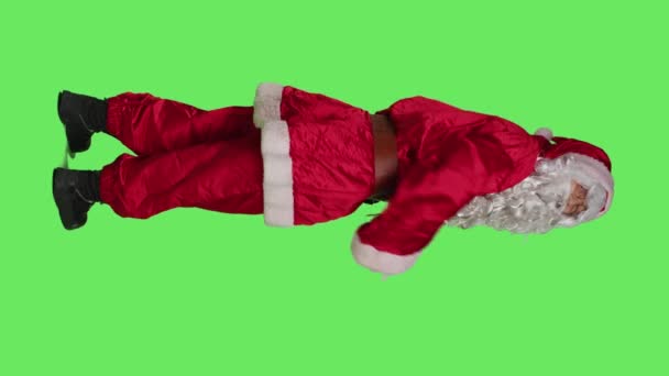 Vertical video Back view of santa claus doing gesture with hands, calling someone to come over and accompany him. Saint nick character in suit hailing person to join, full body greenscreen backdrop - Footage, Video