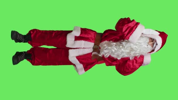 Vertikální video Přední pohled Santa Claus je nemocný bolestí hlavy, necítí dobře během vánočních svátků na celotělovém zeleném plátně. Mladý muž v sezónním červeném kostýmu, trpící bolestmi - Záběry, video
