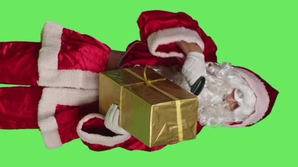 Függőleges videó Elülső nézet a szent nick karakter szkennelés ajándék doboz zöld háttér, a szkenner ajándékok csomagokban. Mikulás claus készül terjeszteni karácsonyi szellem télen - Felvétel, videó