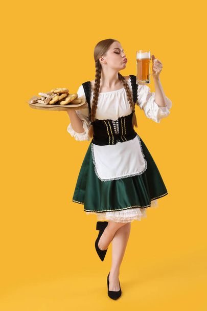 Красива жовтнева офіціантка з пивом і закусками на жовтому тлі - Фото, зображення