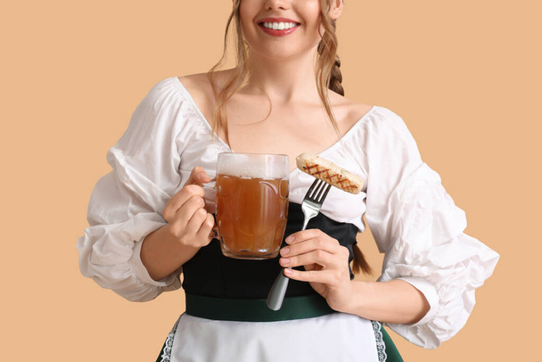 Hermosa camarera Octoberfest con cerveza y salchicha sobre fondo beige, primer plano - Foto, imagen