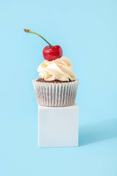 Decorative stand with tasty cherry cupcake on blue background - Foto, Imagen