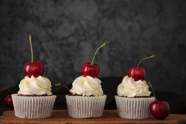 Placa de madeira com cupcakes de cereja saborosos no fundo preto - Foto, Imagem