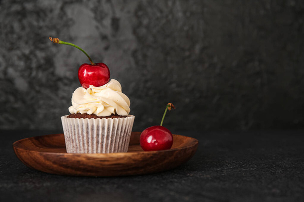 Plate with tasty cherry cupcake on black background - Foto, immagini