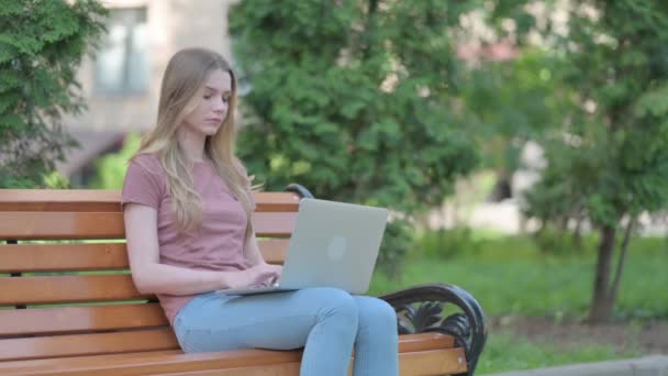 Fiatal nő csuklófájdalommal Laptopon dolgozik, miközben a szabadban ül egy padon - Felvétel, videó