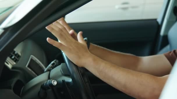 Zijaanzicht medium close-up van vrolijke jonge man uit het Midden-Oosten zittend in nieuwe auto die stuurwiel aanraakt - Video