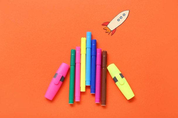 Markers with paper rocket on red background - Photo, image