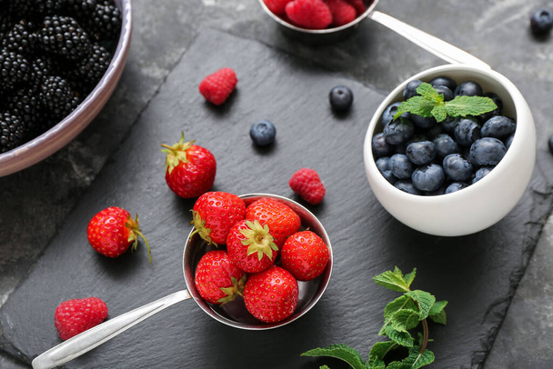 Composition with different fresh berries on grey background, closeup - Fotó, kép