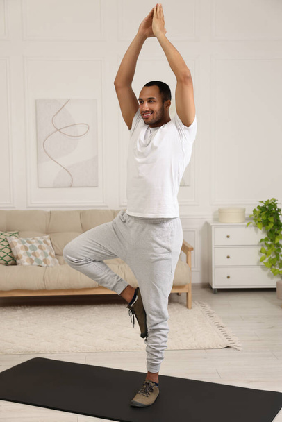 Man doing morning exercise on fitness mat at home - 写真・画像