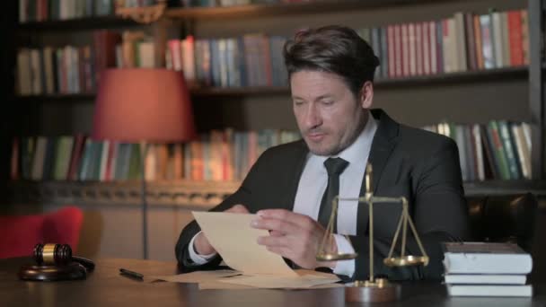 Abogado masculino emocionado leyendo documentos legales en la oficina ante el tribunal - Metraje, vídeo