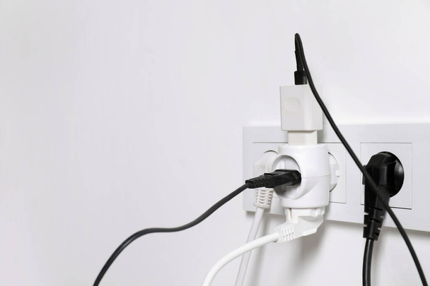 Many different electrical power plugs in sockets on light wall, space for text - Фото, зображення