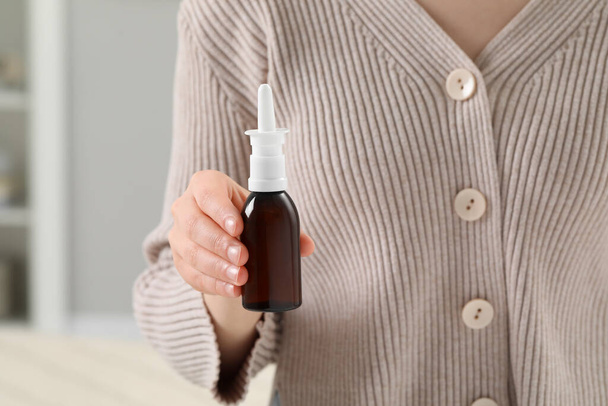 Woman holding nasal spray indoors, closeup view - Foto, immagini