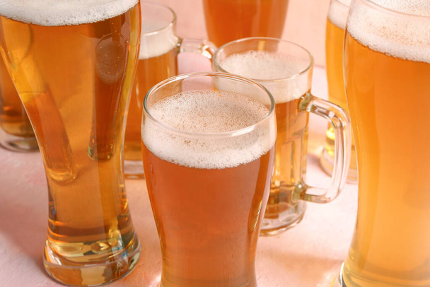 Γυαλιά και κούπες κρύας μπύρας σε μπεζ φόντο. Γιορτή Οκτωβρίου - Φωτογραφία, εικόνα
