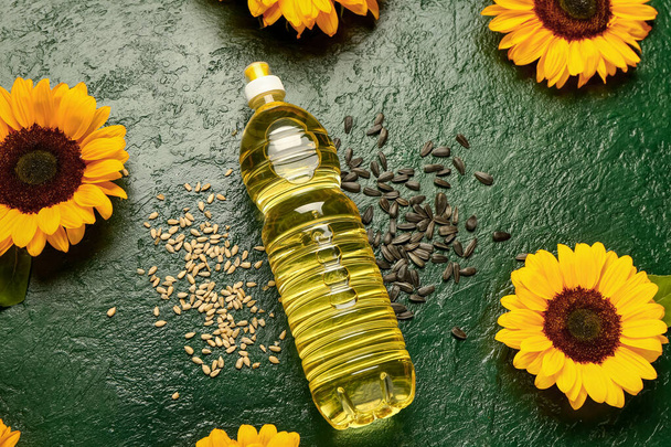 Girasoles, semillas y botella de aceite sobre fondo verde - Foto, imagen