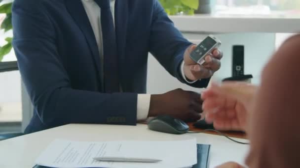 Mittelschnitt-Aufnahme eines nicht wiederzuerkennenden Mannes, der mit seiner Frau am Schreibtisch vor einem Verkäufer sitzt, der erfolgreich ein neues Auto kauft - Filmmaterial, Video