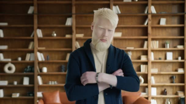 Muotokuva onnistunut liikemies tai startup yrittäjä rento villatakki poseeraa parvi huoneisto kirjaston taustalla. Mies vakavasti katsot kamera, kädenylitys, ja silmiinpistävää aiheuttaa 4K hidas - Materiaali, video