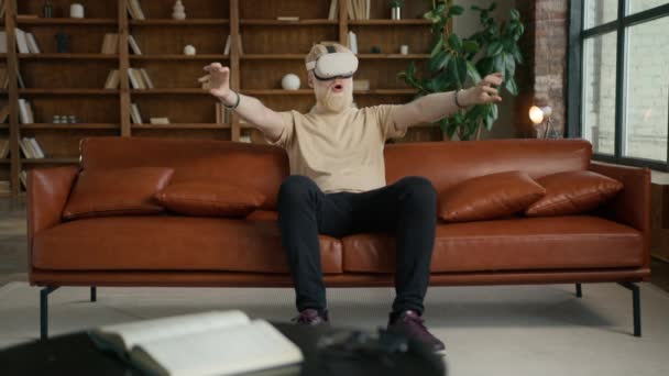 3D tartalom létrehozása Mérnök visel Virtuális valóság headset dolgozik otthon iroda. Szakállas fickó kézmozdulatokat tesz kiterjesztett valóság ül kanapén elegáns modern tetőtéri térben nappal - Felvétel, videó