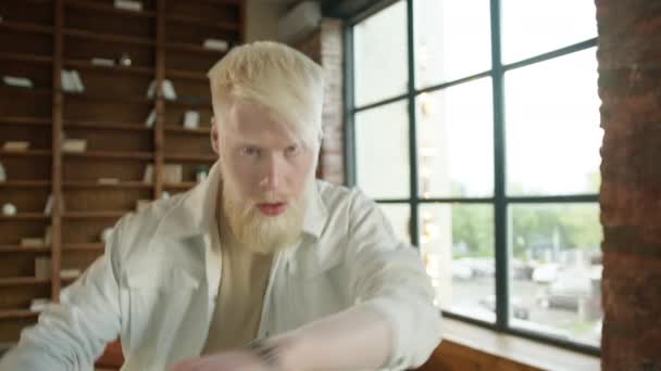 Vreemde albino man verloor het contact met de buitenwereld, trekken zich terug in zichzelf vanwege techno muziek in stedelijke stijl huis. Jonge dronken man met baard actief dansen in loft design appartement achtergrond - Video