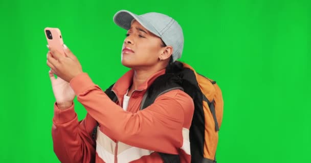 Hiking, woman and phone with problem on green screen while upset or frustrated with network service. Young female model person with a backpack and smartphone on a studio background for connection. - Footage, Video