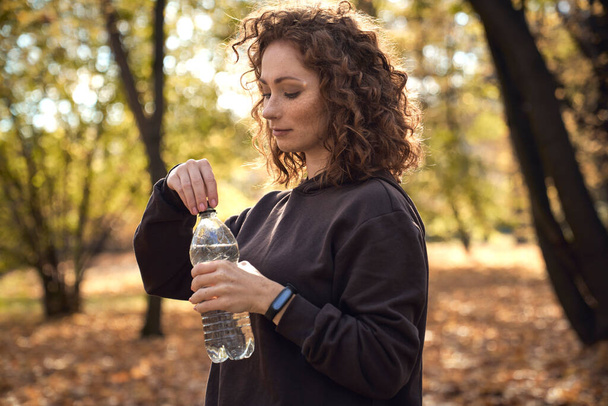 Vista lateral de la mujer pelirroja caucásica a punto de beber agua - Foto, Imagen
