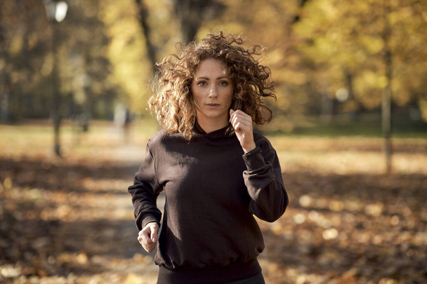 Umsichtige Kaukasierin joggt im Herbst im Park - Foto, Bild
