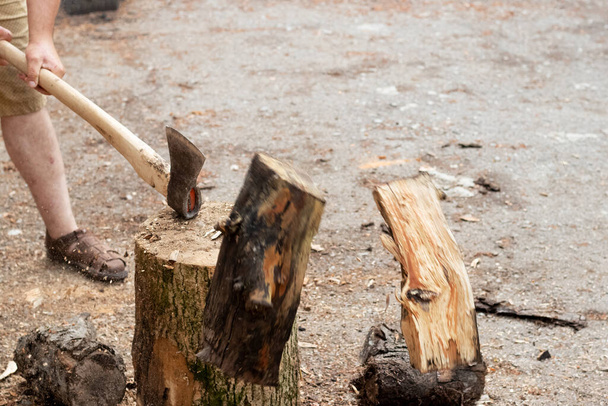A man chops firewood with a large axe in the summertime - Foto, immagini