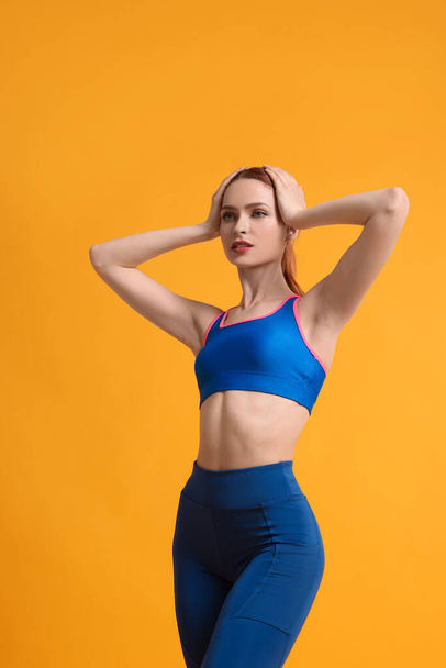 Young woman wearing sportswear on yellow background - Foto, afbeelding
