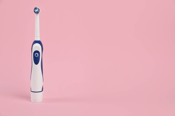 Electric toothbrush on pink background, space for text - 写真・画像